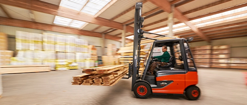 Gabelstaplerfahrer bringt frisches Schnittholz durch die Halle – effiziente Logistik im Holzhandel.
