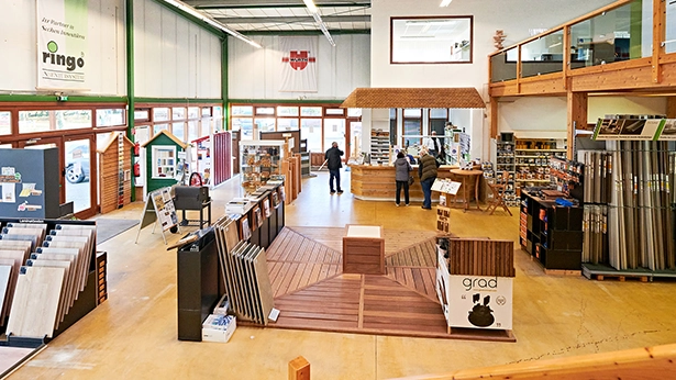 Großzügige Indoor-Ausstellung im Holzhandel mit verschiedenen Bodenbelägen, Terrassenmustern und Holzprodukten.