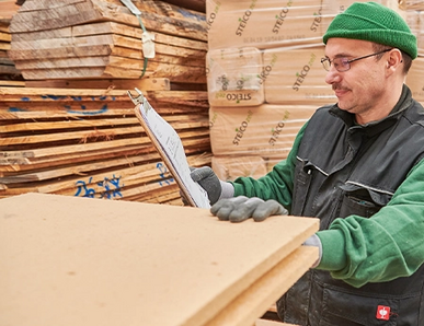 Mitarbeiter kontrolliert Holzfaserdämmplatten im Lager – natürliche Dämmstoffe für nachhaltiges Bauen.