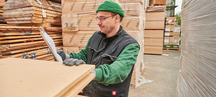 Mitarbeiter kontrolliert Holzfaserdämmplatten im Lager – natürliche Dämmstoffe für nachhaltiges Bauen.