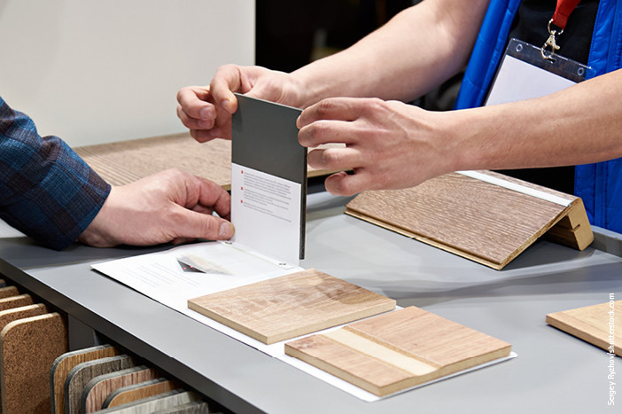 Kundenberatung im Fachhandel: Zwei Personen begutachten verschiedene Materialmuster für Bodenbeläge.