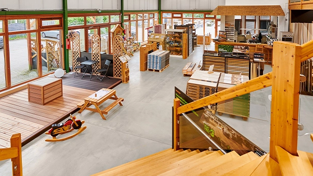 Blick von der Treppe auf den Ausstellungsbereich mit Terrassendielen, Gartenzubehör und Mustermaterialien.
