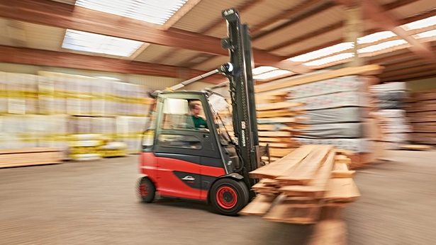 Gabelstapler in Bewegung transportiert Holzleisten durch das Lager – dynamische Aufnahme mit Bewegungsunschärfe.